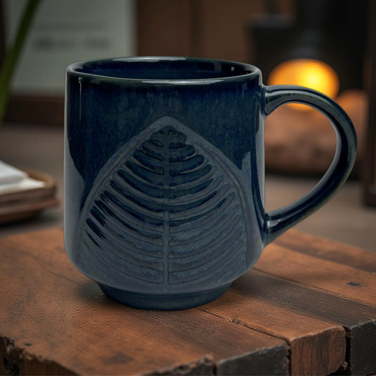 Blue ceramic mug with leaf design on a wooden surface