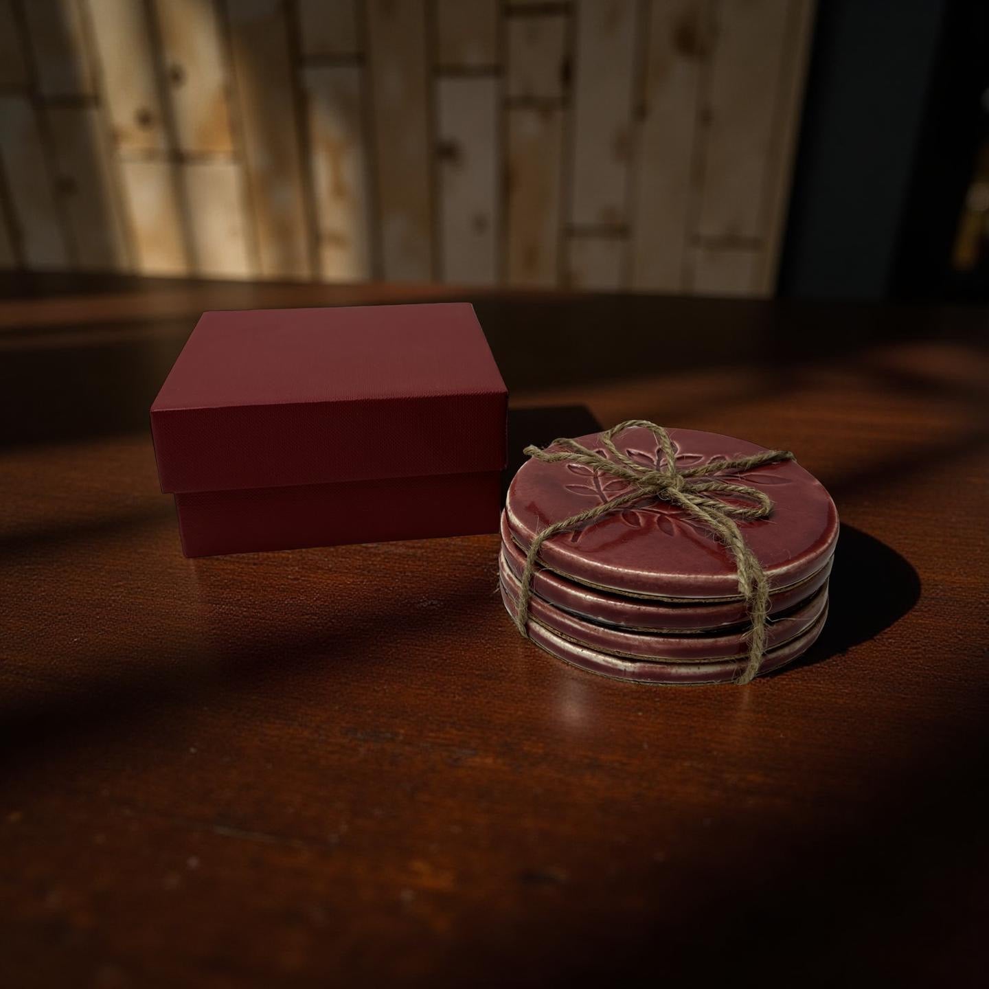 Stack of red coasters tied with twine on a wooden surface next to a red box.